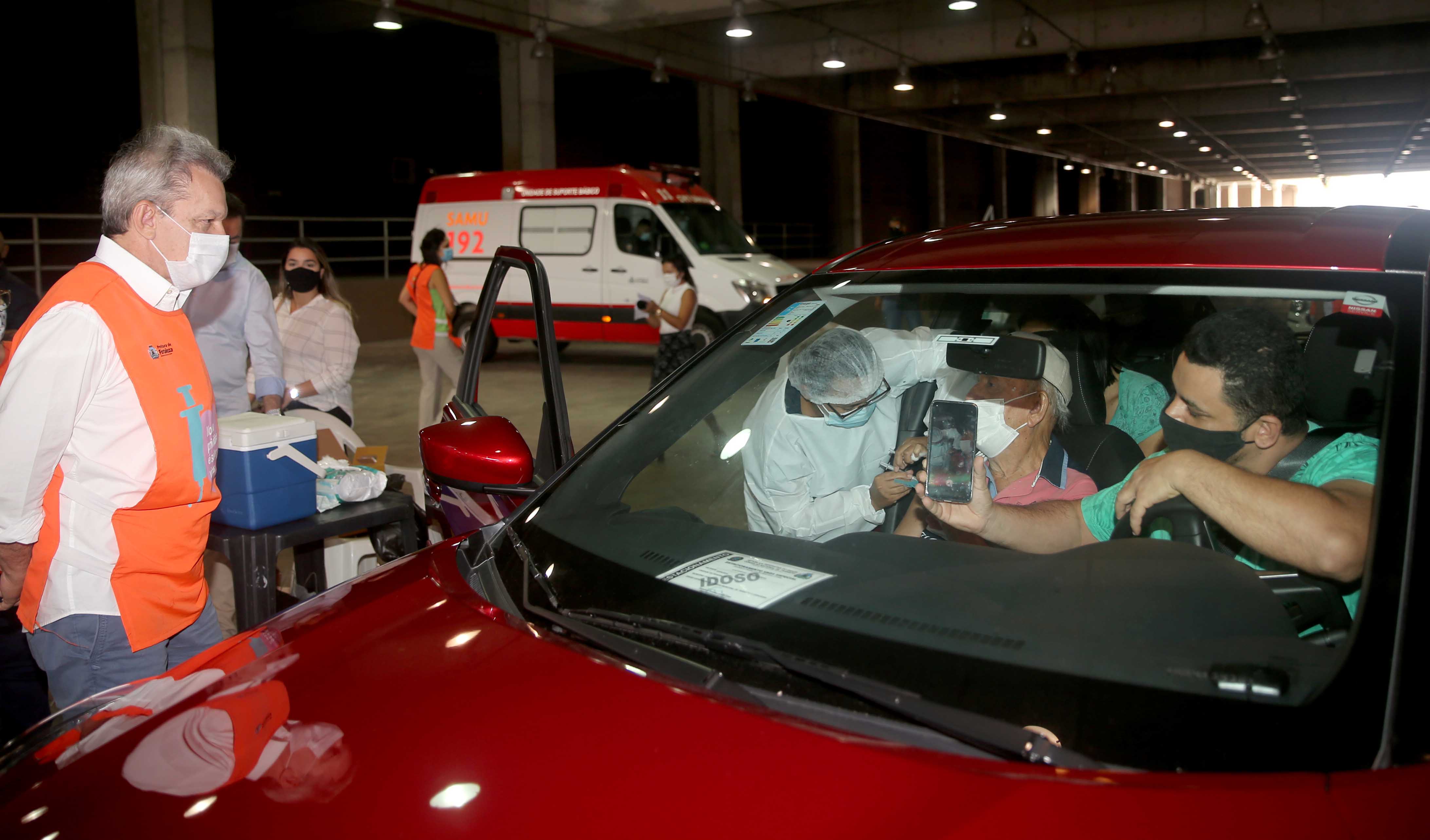 Sarto observa um senhor sendo vacinado dentro de um carro